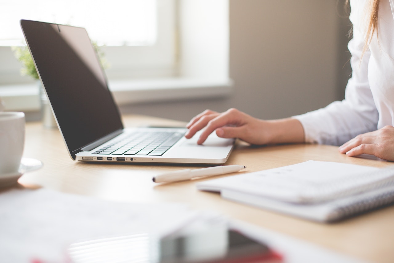 Woman working on laptop with pencil and notebook next to her