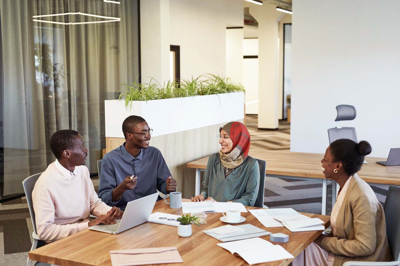 Four insurance employees of color around a table at work