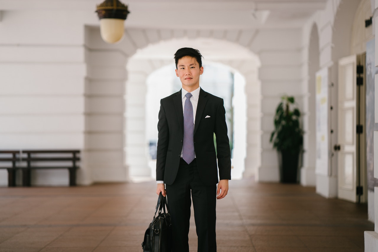 New insurance agency hire walking in courtyard with briefcase and suit