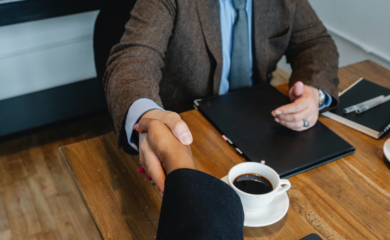 Insurance producer signing agreement and shaking hands with agency owner