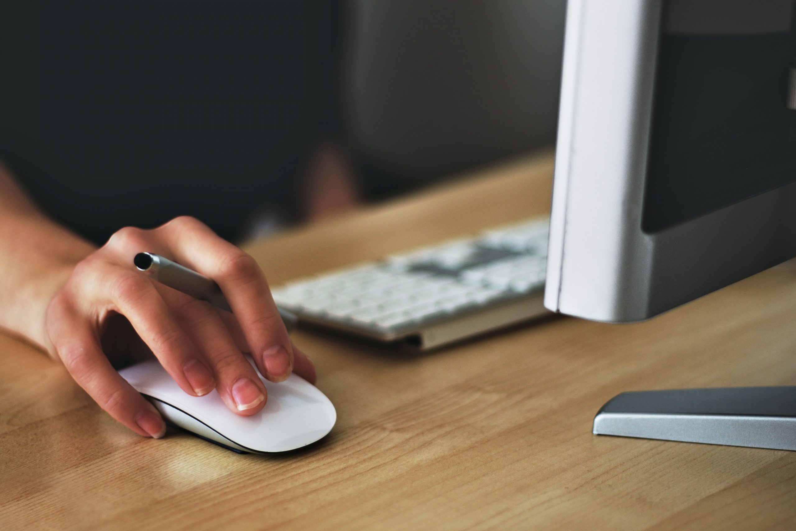 hand holding mouse and pen at desktop computer
