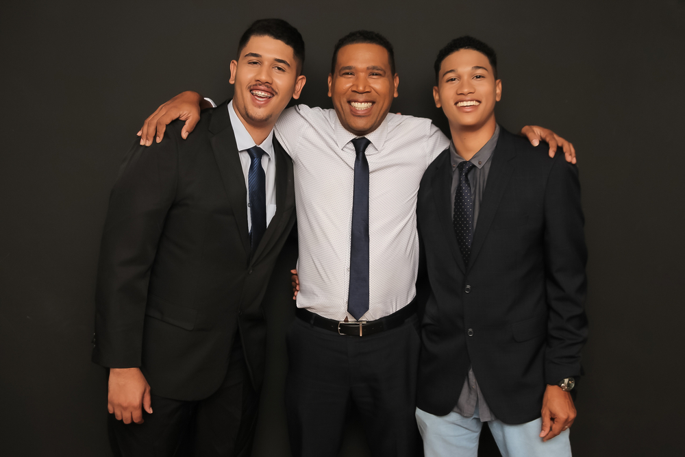 Father holding two sons by the shoulder while working at an insurance agency together