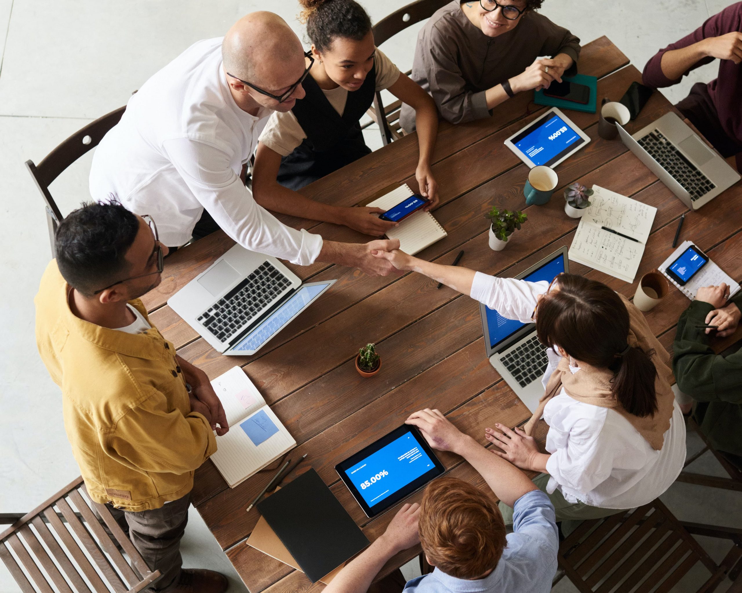 New coworkers shaking hands over a table in a meeting after agency merger