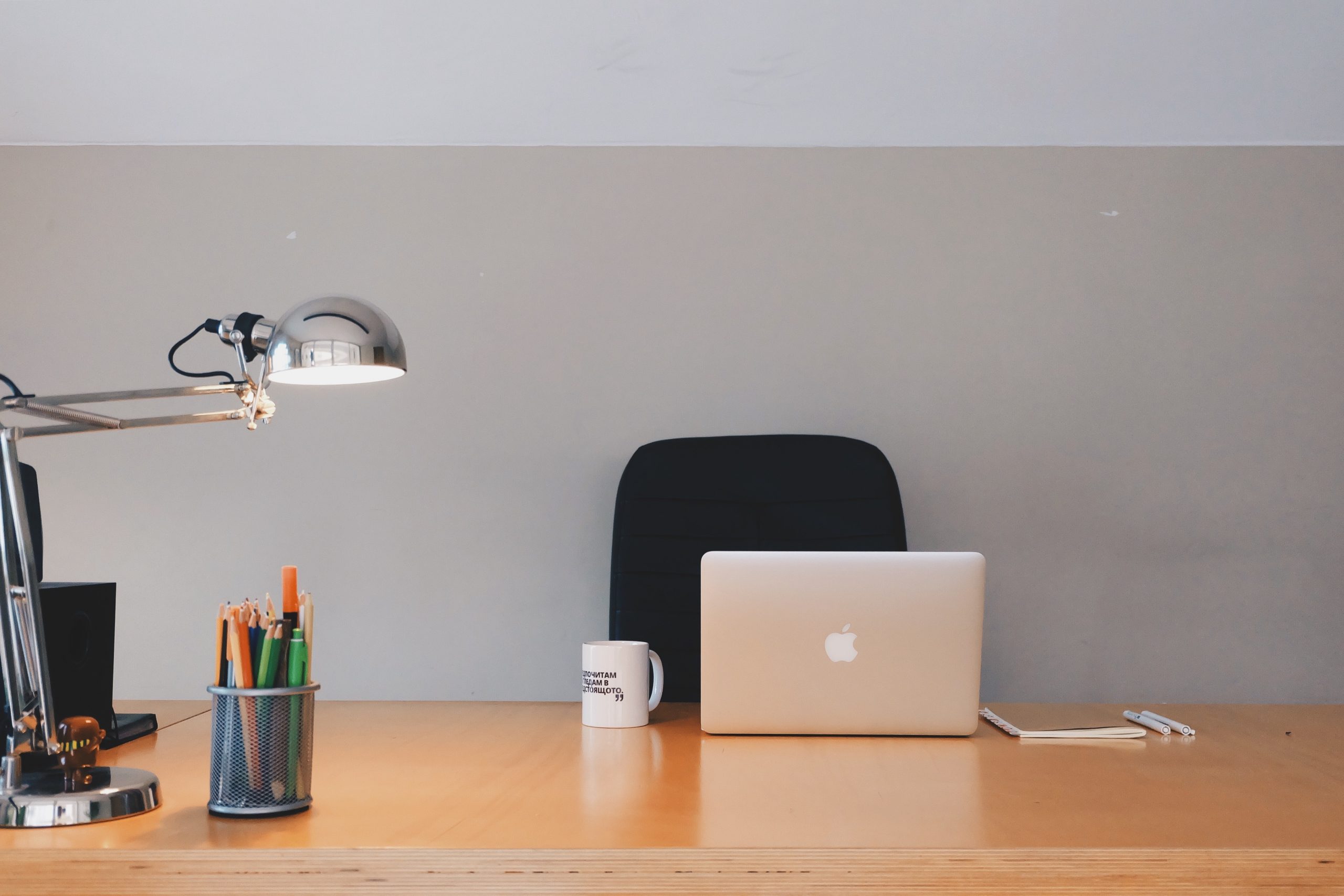 Clean but empty cubicle in an office with laptop and coffee mug